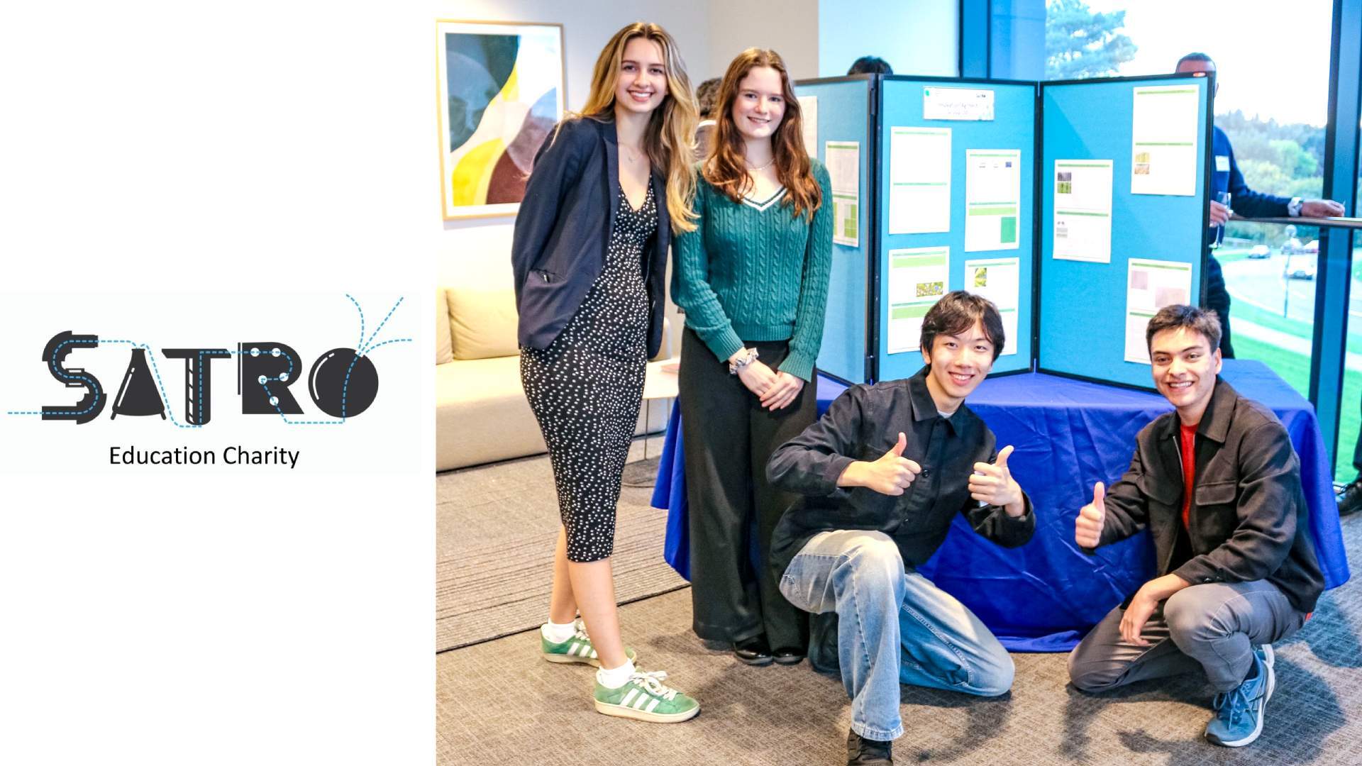 A group of four students pose next to a poster for their industry project