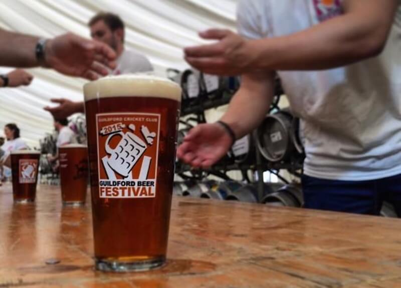 A beer glass on a bar with the logo for the Guildford Beer Festival